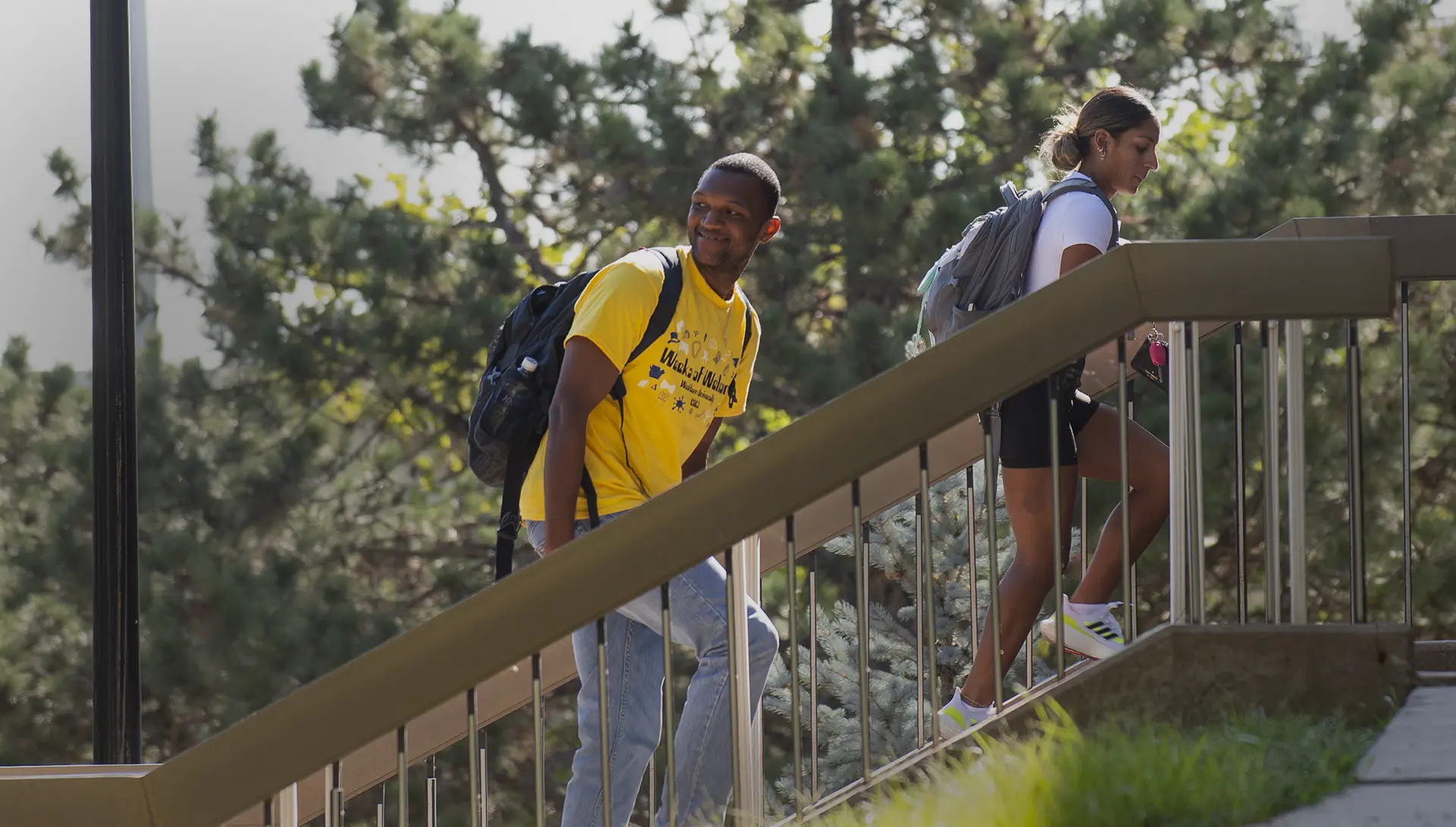 A student smiles over his shoulder while walking up the stairs to the library.