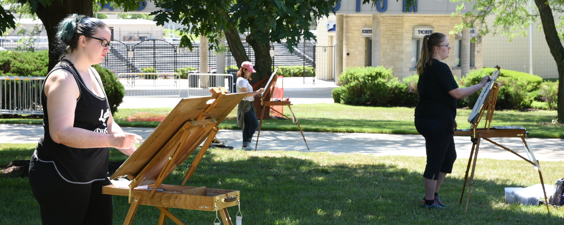 Three students drawing on easels on Union Lawn