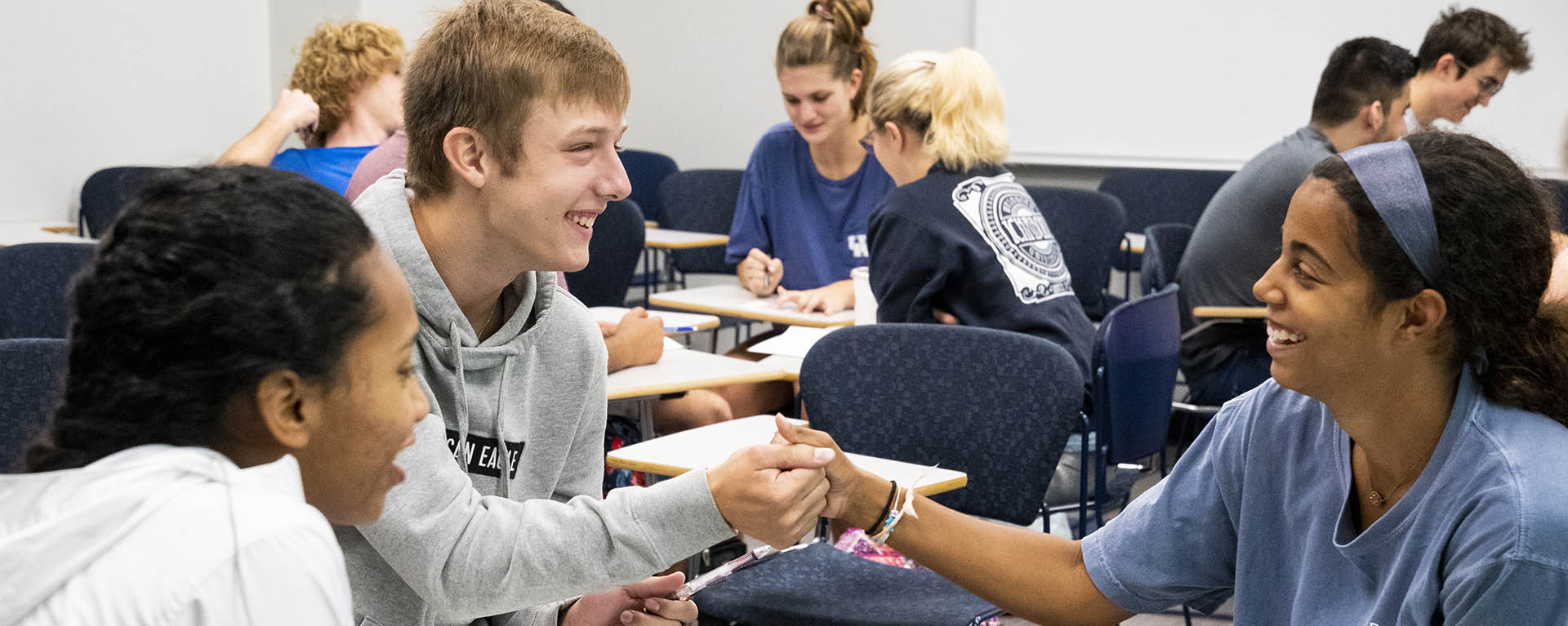 Students laugh and shake hands during a group discussion during class