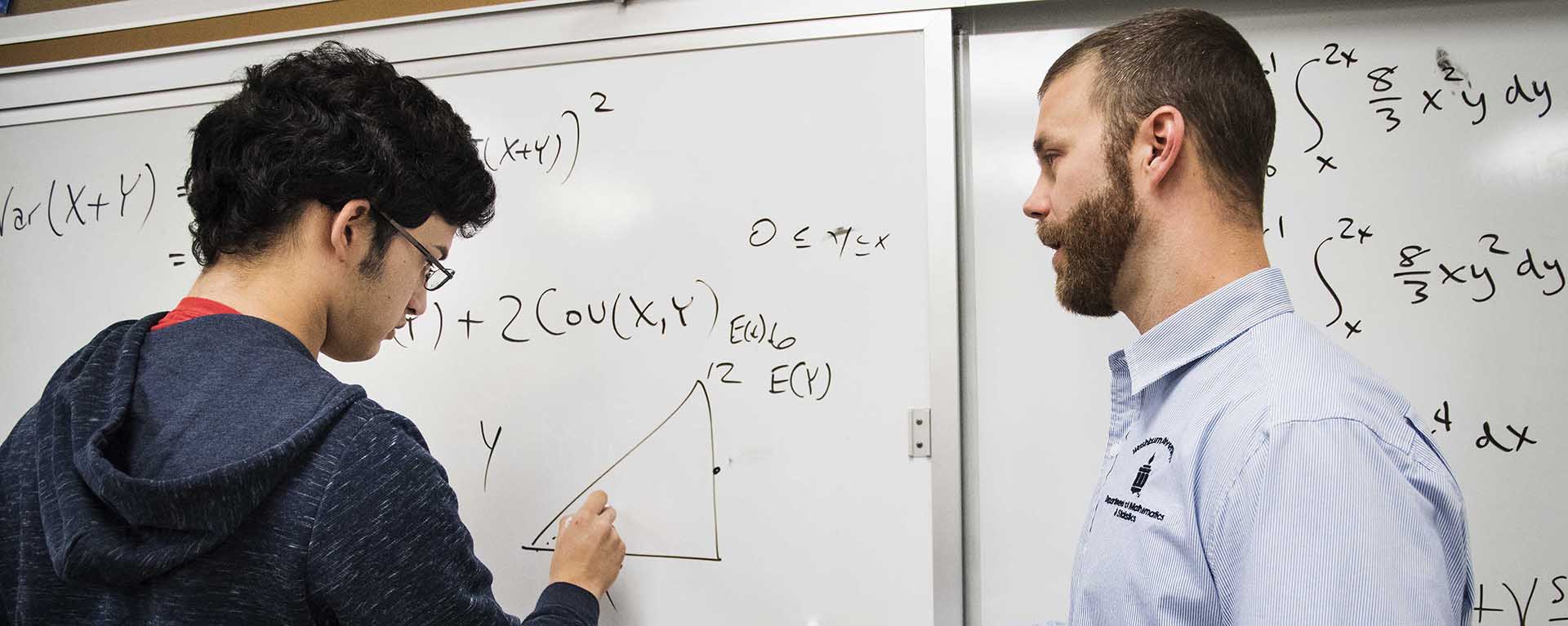 A math professor works with a Washburn student on a formula during class.