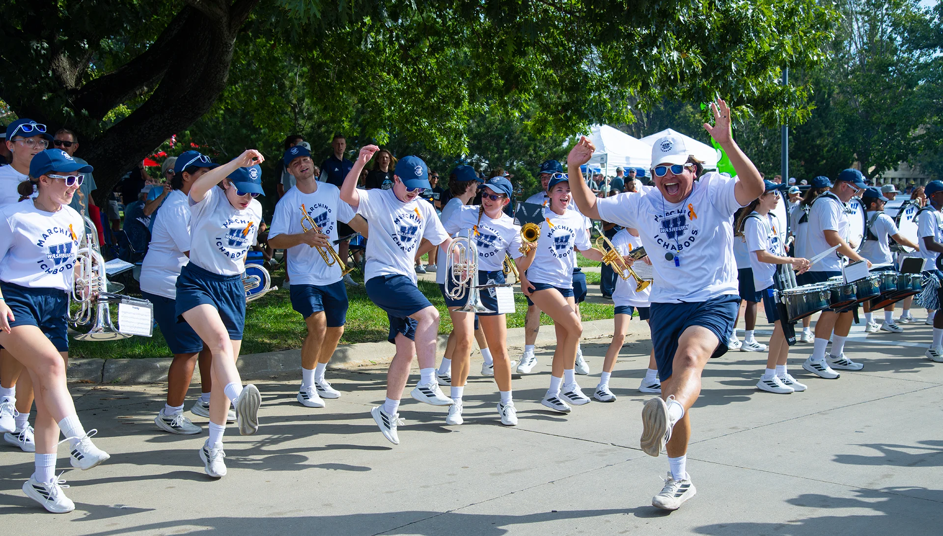 Washburn marching band members dance while performing at a tailgate.