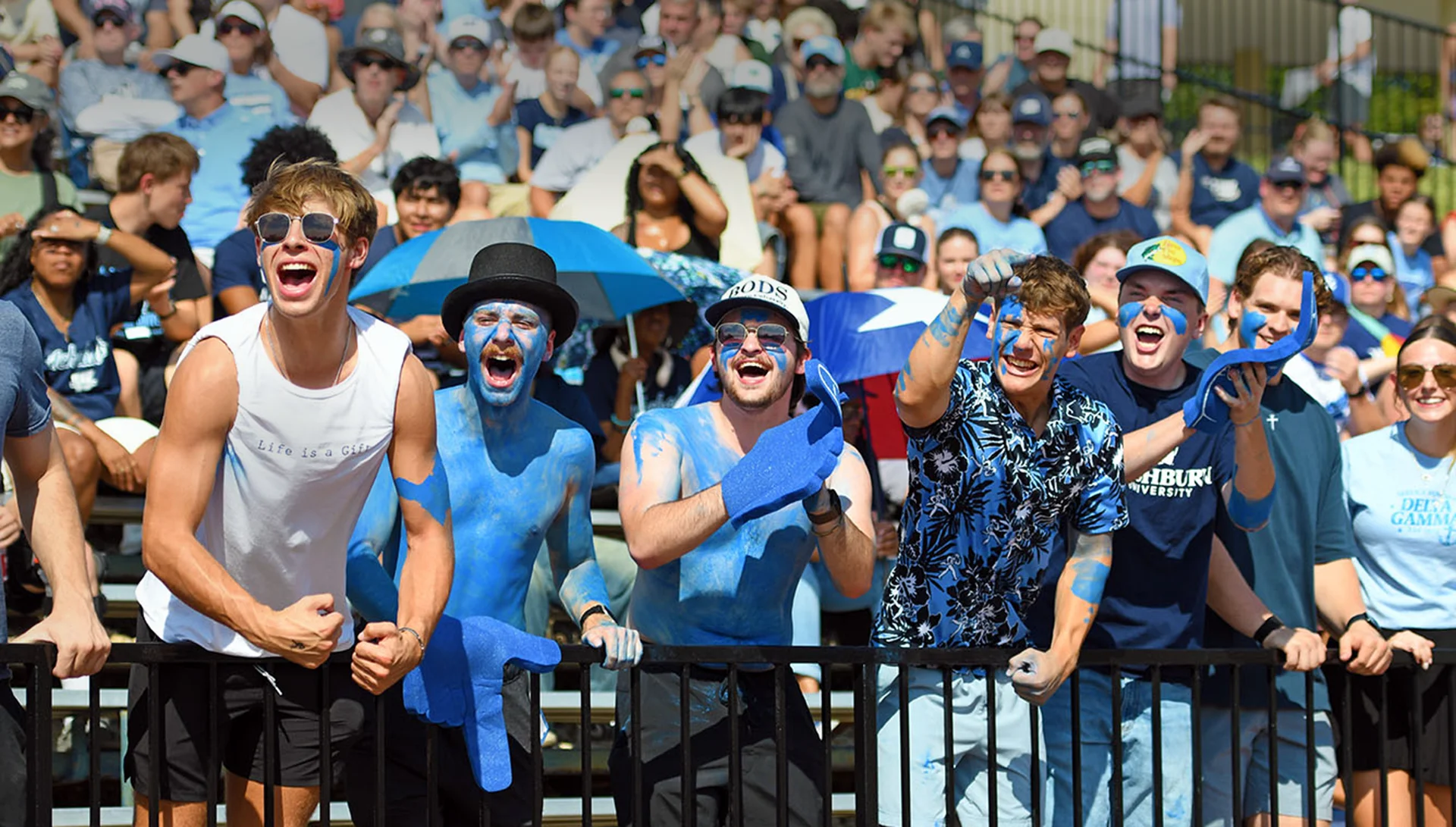 Washburn students cheer at a football game while being painted up blue.