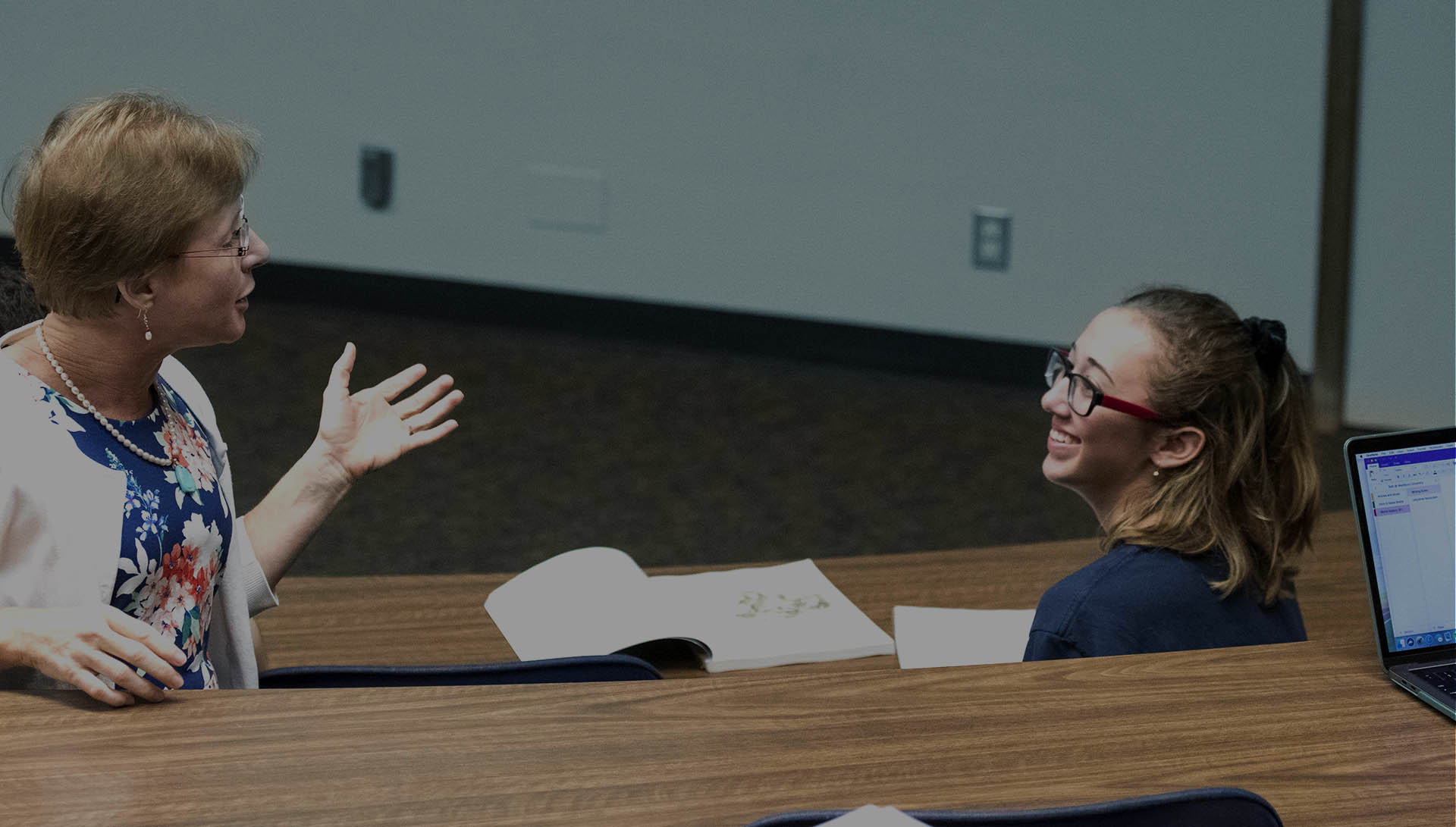Professor with student speaking together in classroom