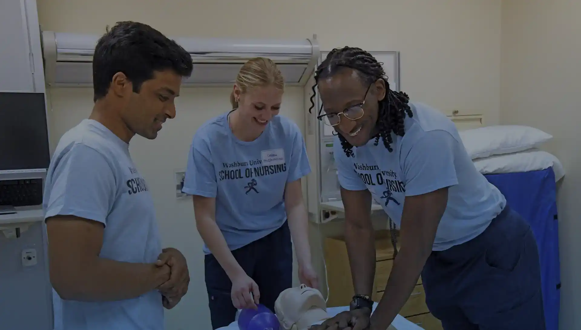 A group of Washburn students smile as they walk on campus with the bell tower behind them.