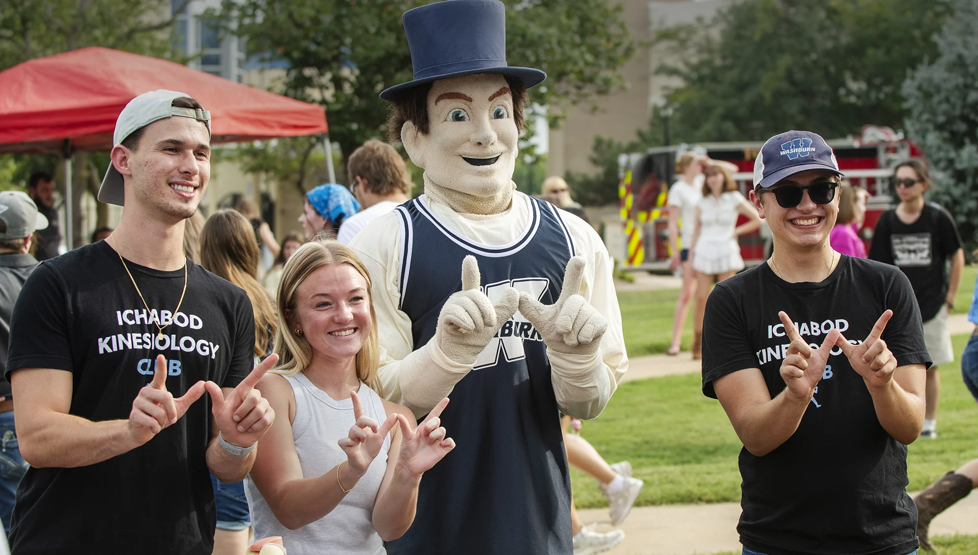 Washburn students pose with Mr. Ichabod while making a W with their hands.