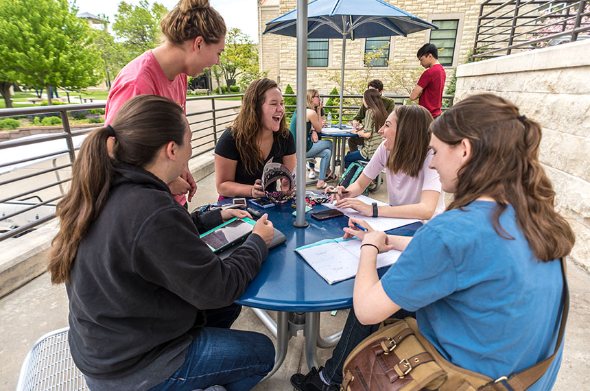 students seated outdoors at table laughing