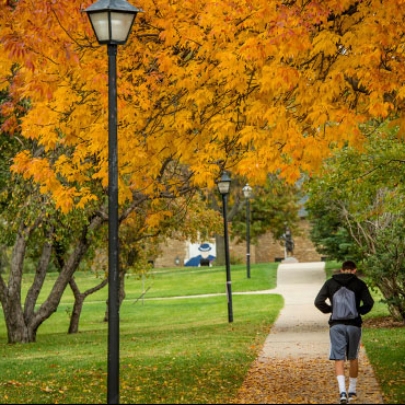 A student walking on campus in the fall