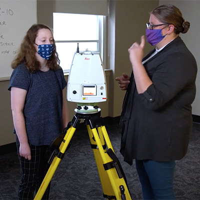 Emma and a professor look at a digital scanner used for investigations