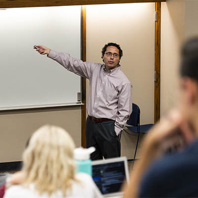 An economic professor points while giving a lecture.