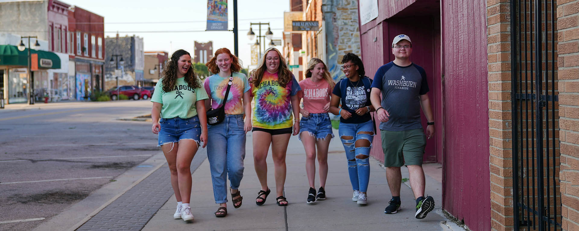 Students laugh and chat while walking down the sidewalk in NOTO.