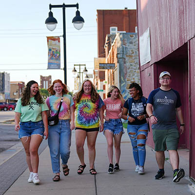 Students laugh and talk while walking down a street in North Topeka.