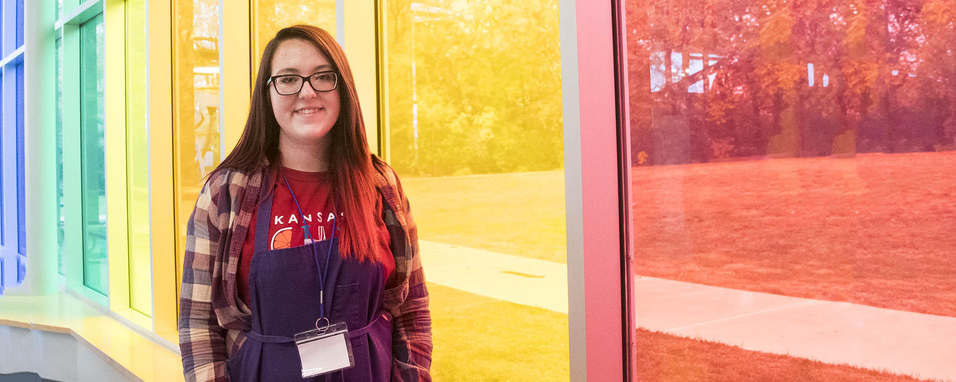 apeiron student smiling in front of colorful windows