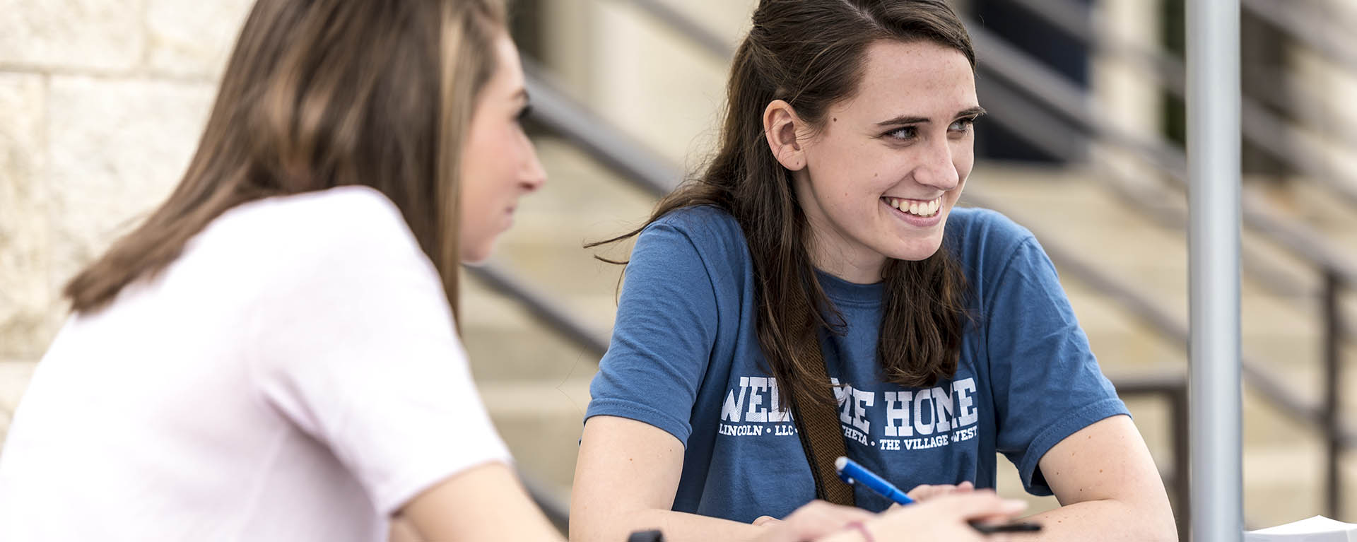 A student smiles while sitting with friends.