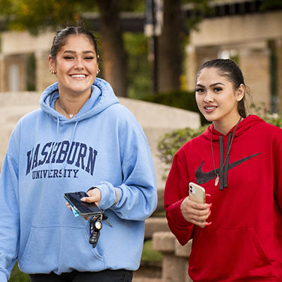 Two students laughing outside on a sunny day