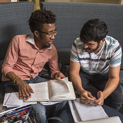 Two students talk while working on homework on campus.