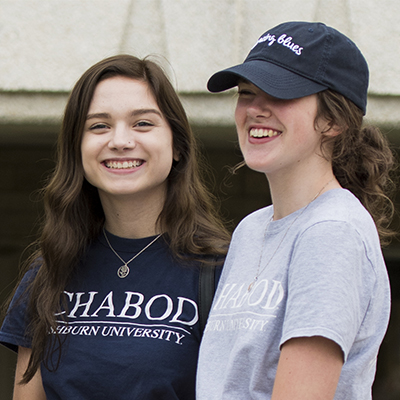 Two students laughing outside on a sunny day