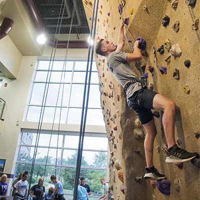 A student climbing the rock wall
