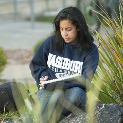 A Washburn student works on an art project by the Koi Pond on campus