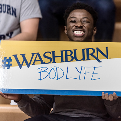 A Washburn students holds up a Bod Life sign during a basketball game at Lee Arena