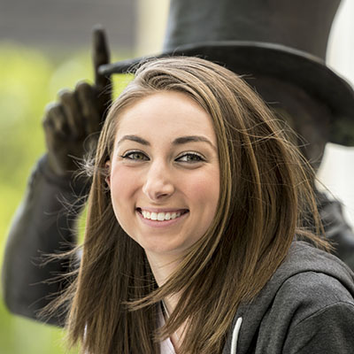 A student smiles with an Ichabod statue behind them.