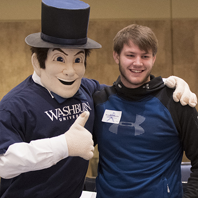A student smiles for a photo while posing with Mr. Ichabod