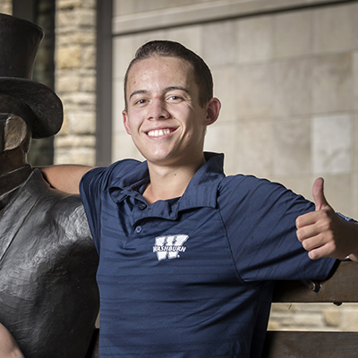 A student smiles and gives a thumbs up.