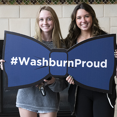 A Washburn student and her sister holding a Washburn sign on Siblings Day.