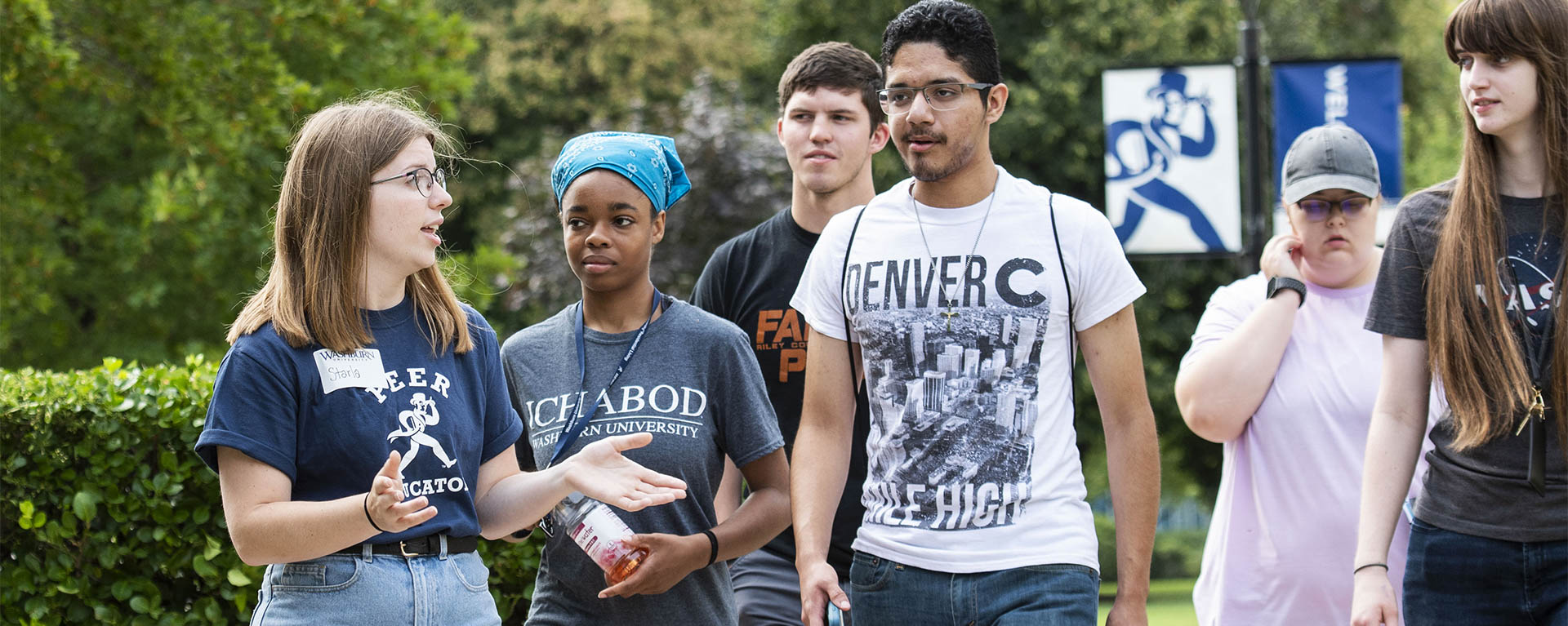 A student wearing a name tag leads a tour group of other students around campus.