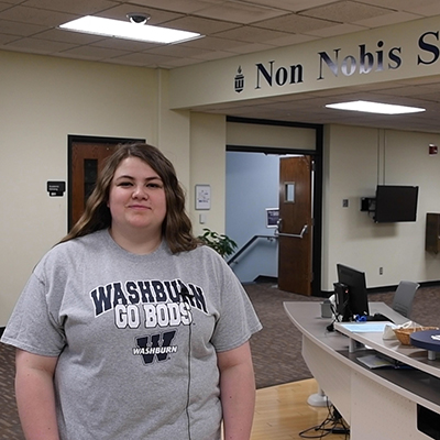 Abby smiling while gesturing around the library