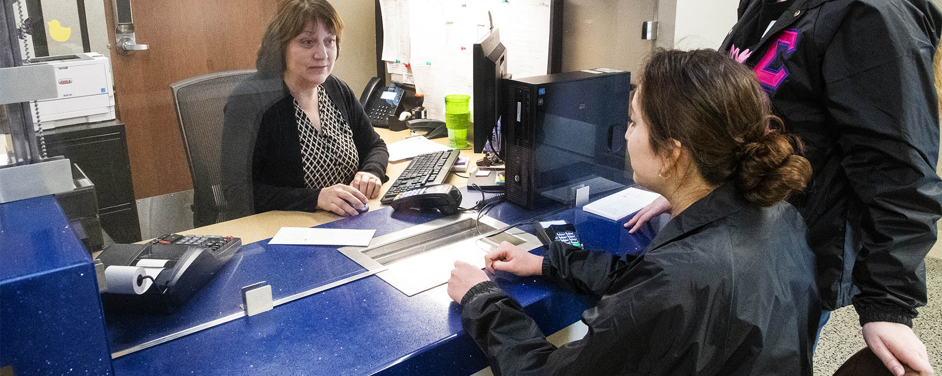 A Washburn student pays her bill at the Business Office window in Morgan Hall.