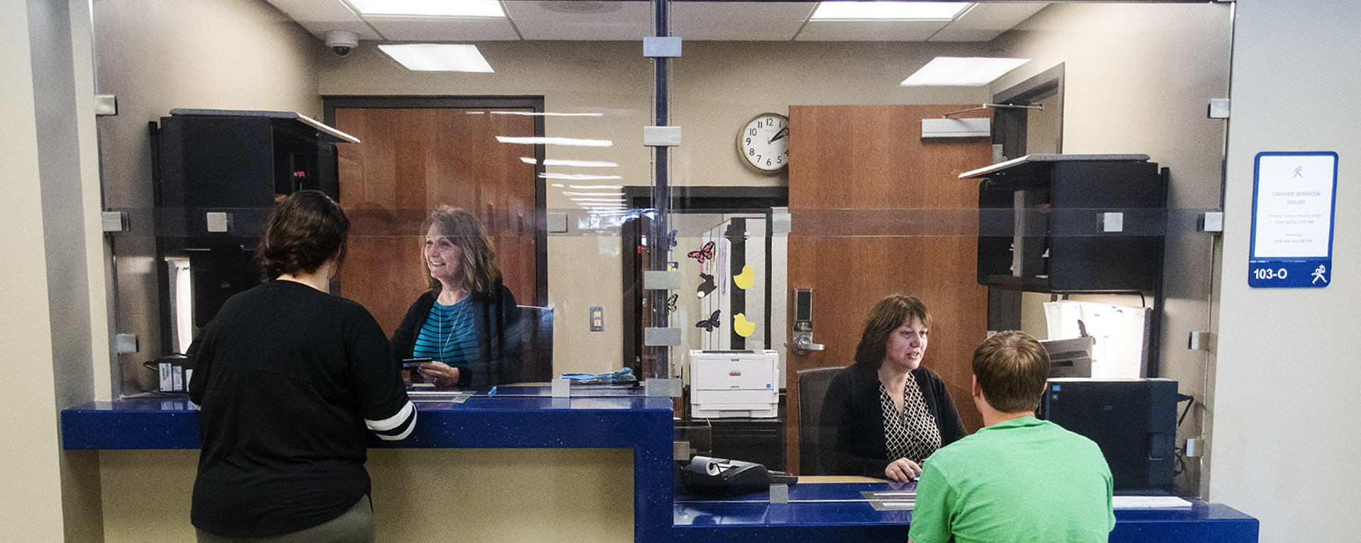 Two students receive help at the Business Office window.