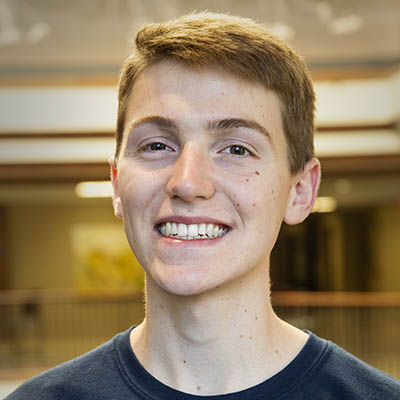 Washburn Summer Orientation Counselor Bryan smiles while wearing a Washburn shirt