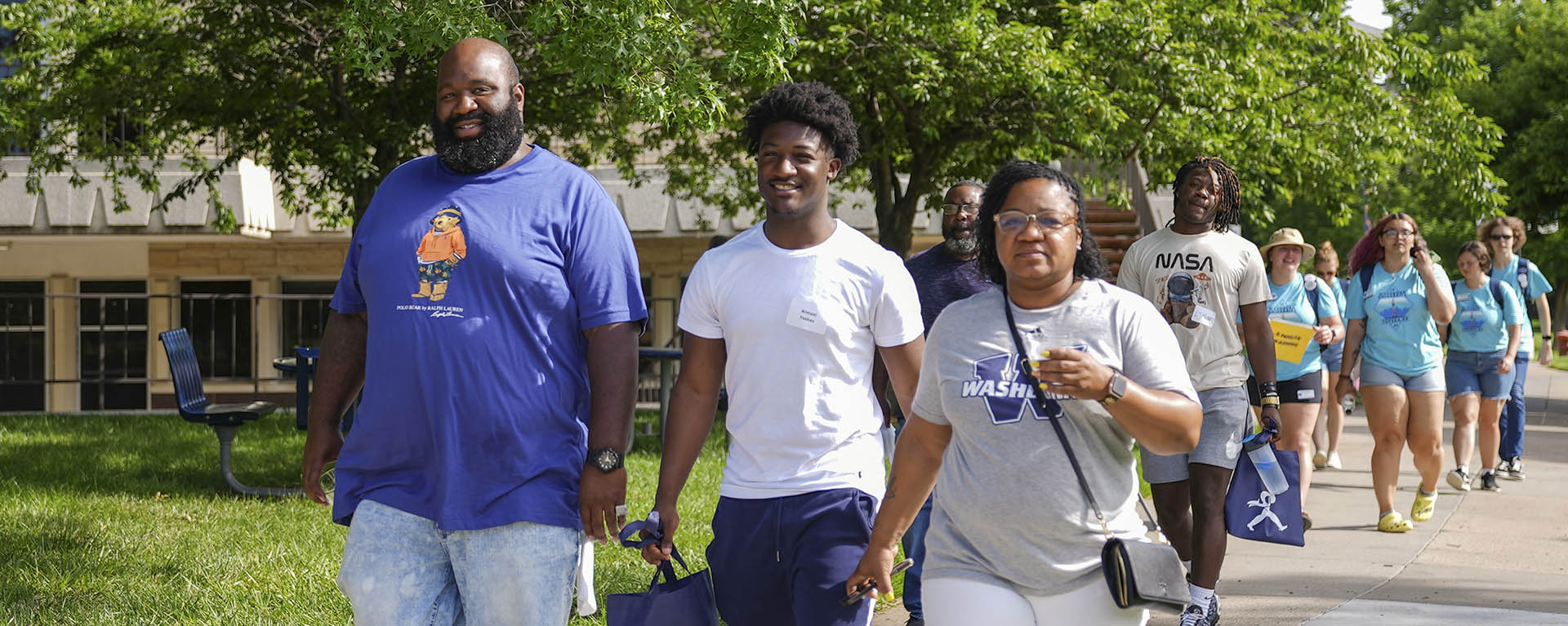 A student leads a tour group of other students around campus.