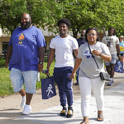 A student with their family walking on campus during orientation.