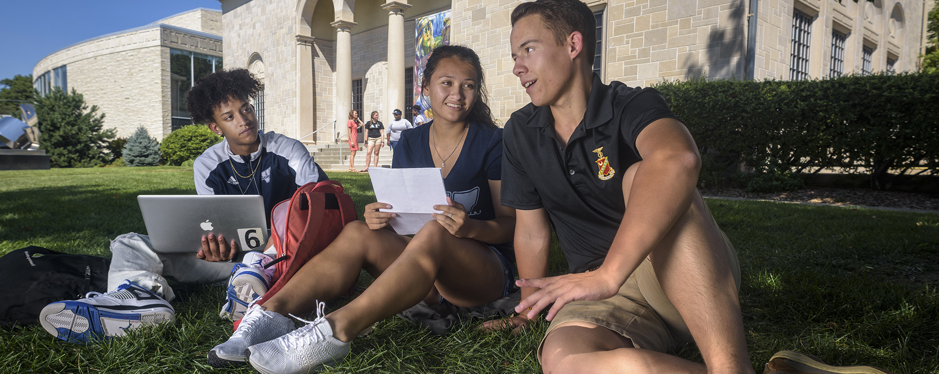 A Washburn student works on her laptop while laying in the grass on the Quad.