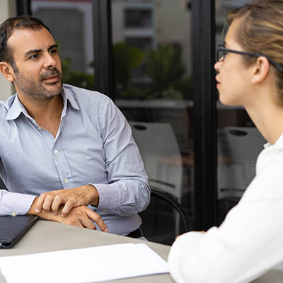 Two people talk at a conference table.