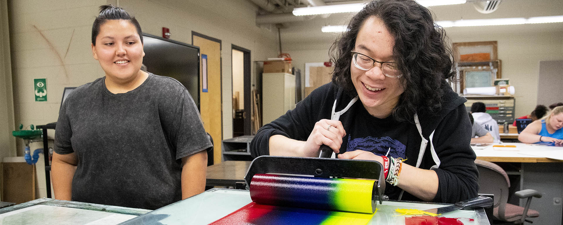 A student laughs while rolling ink during a print making class.