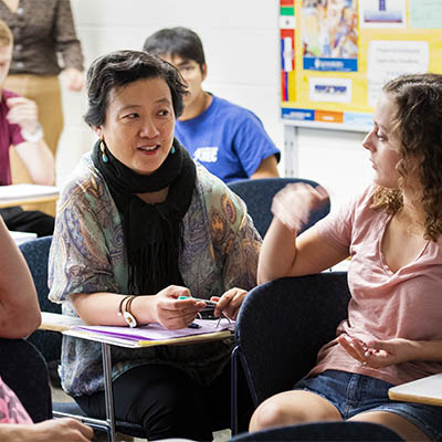 Two students have a discussion while sitting in class.