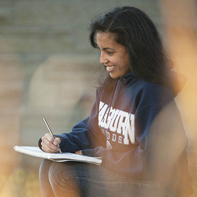 A student smiles while drawing outside.