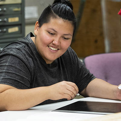 A student smiles while working on a drawing in art class.