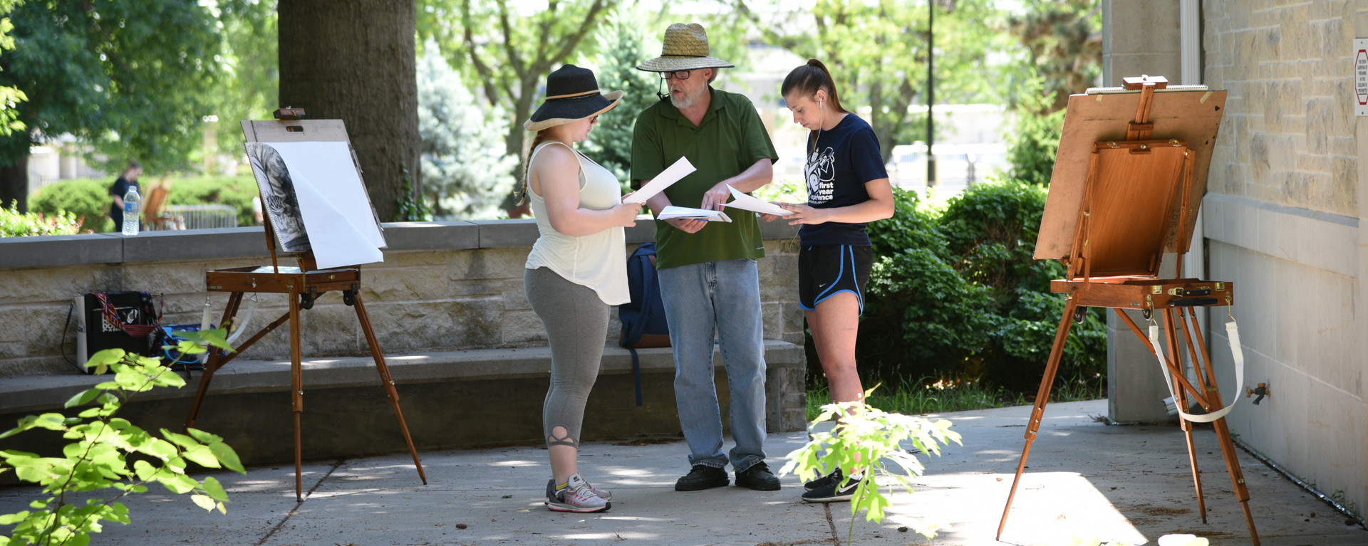 Professor talking with students outside while drawing