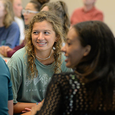 A student smiles while at an orientation for biology.