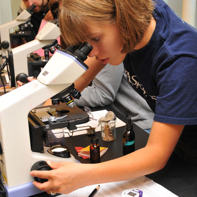 Student viewing slide under a microscope 