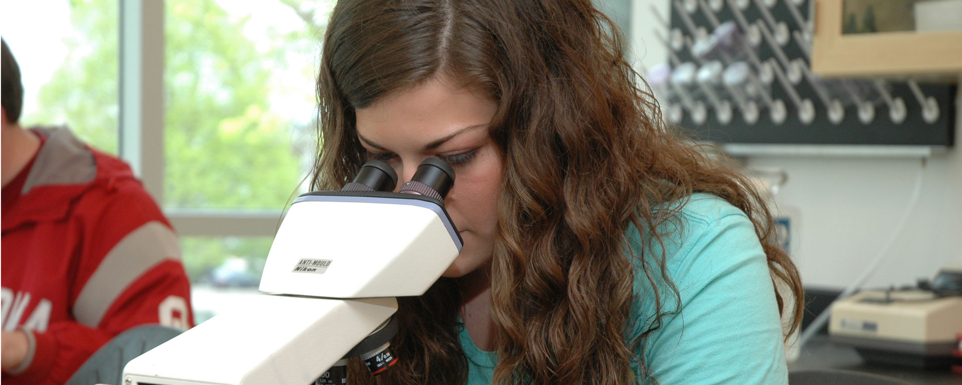 Student using a microscope in biology class.