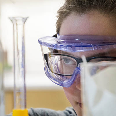 A student closely examines a beaker of liquid