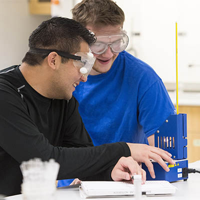Two students laugh while working in the lab