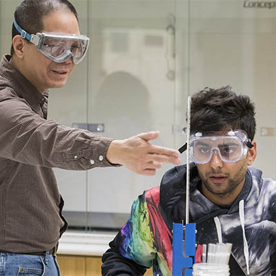 A professor points something out to a student in lab