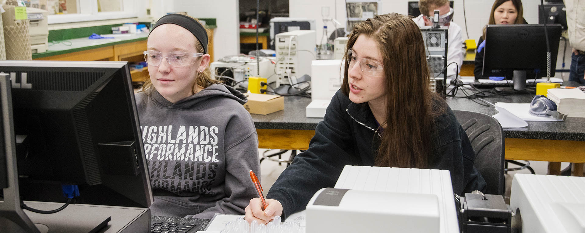 Biochemistry students work on a lab with the help of a professor.