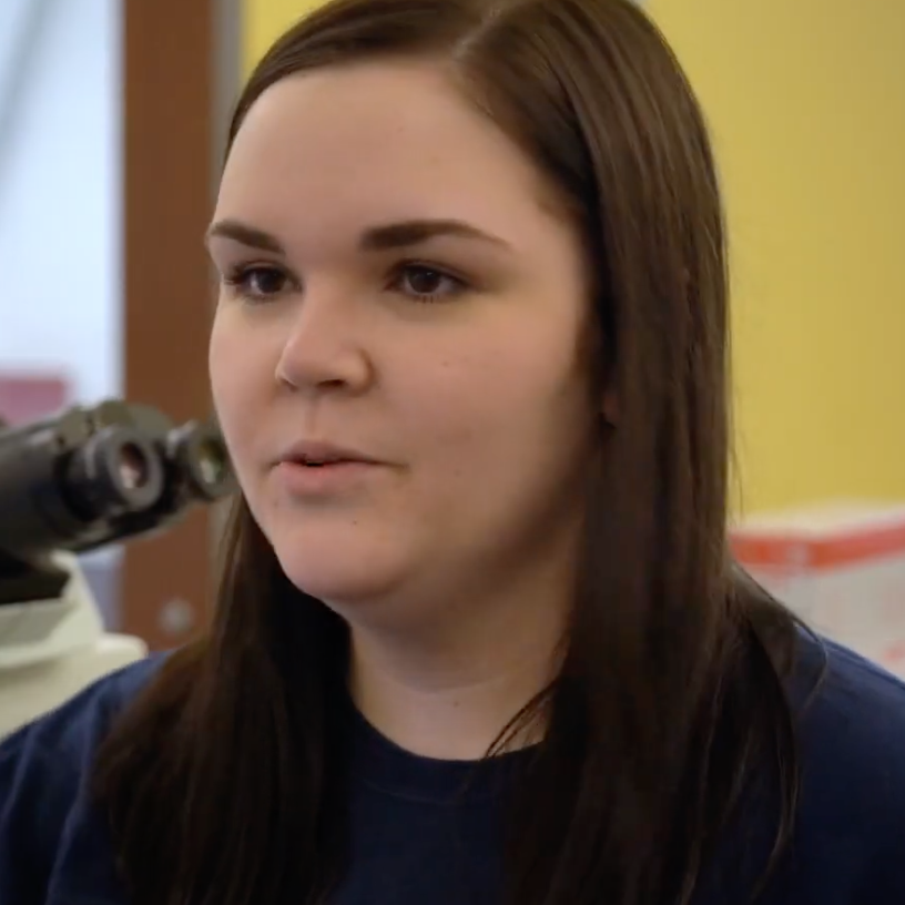 Gretchen smiles while sitting in a lab on campus.