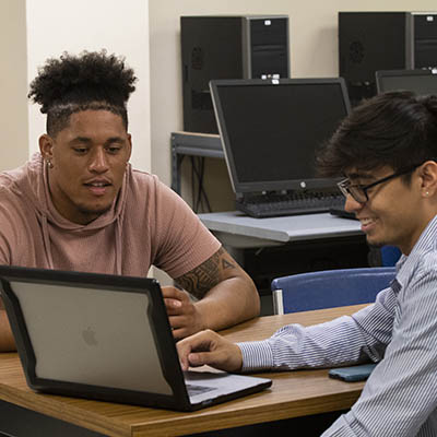 Two students smile while in class.